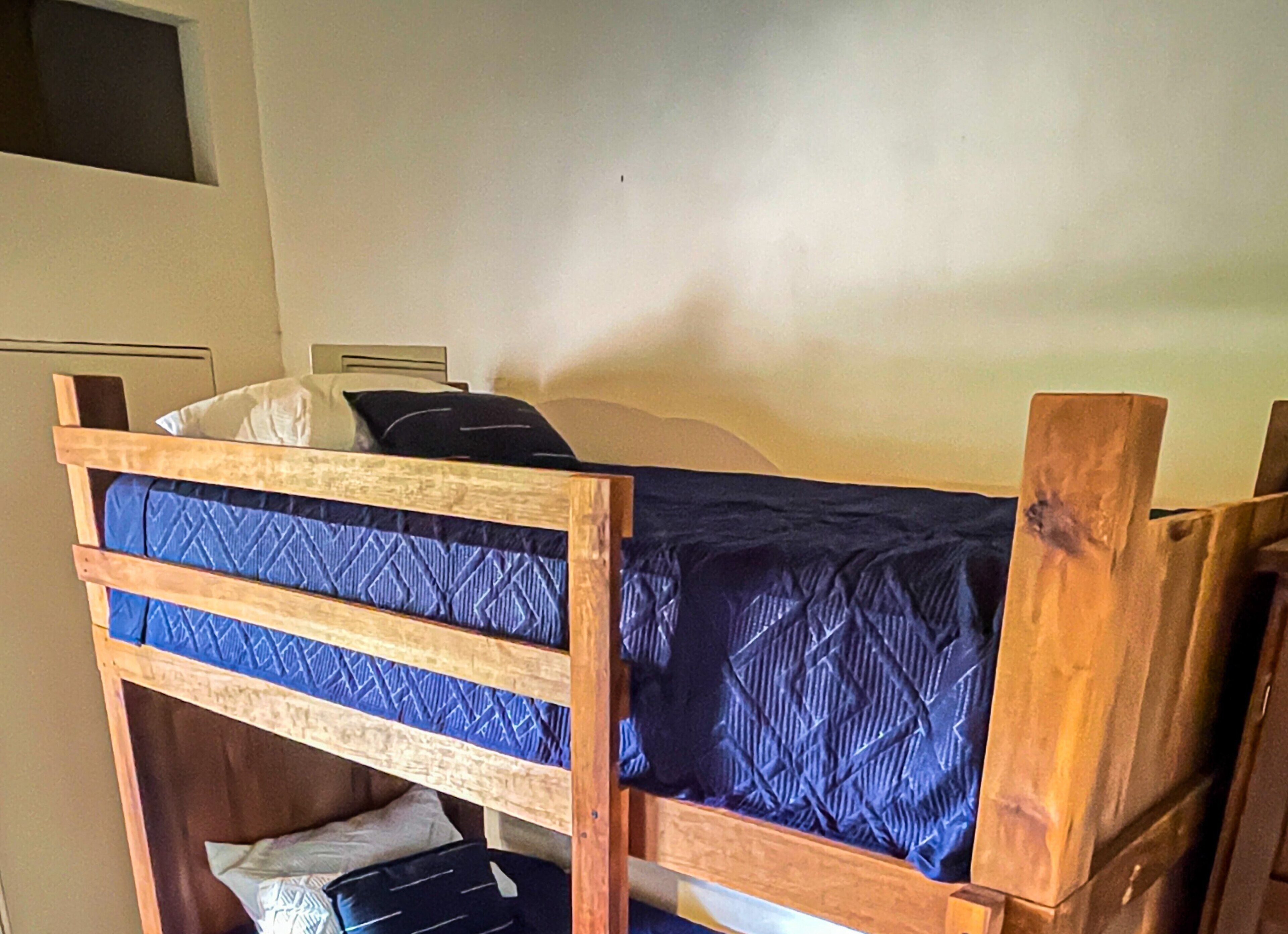 A bunk bed with a wooden frame and blue bedding.