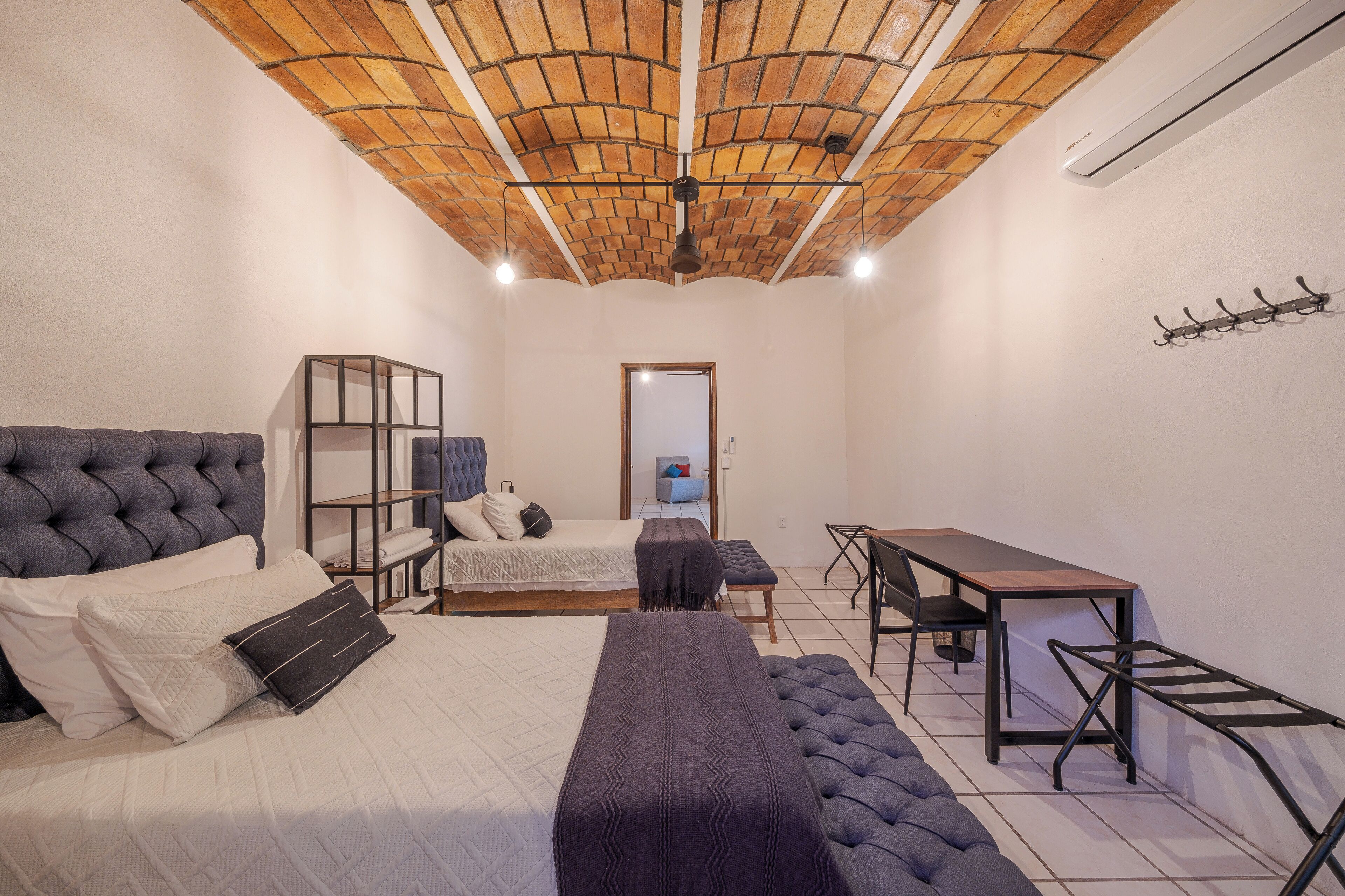 A bedroom with a large bed, a desk, a chair, and a wardrobe.