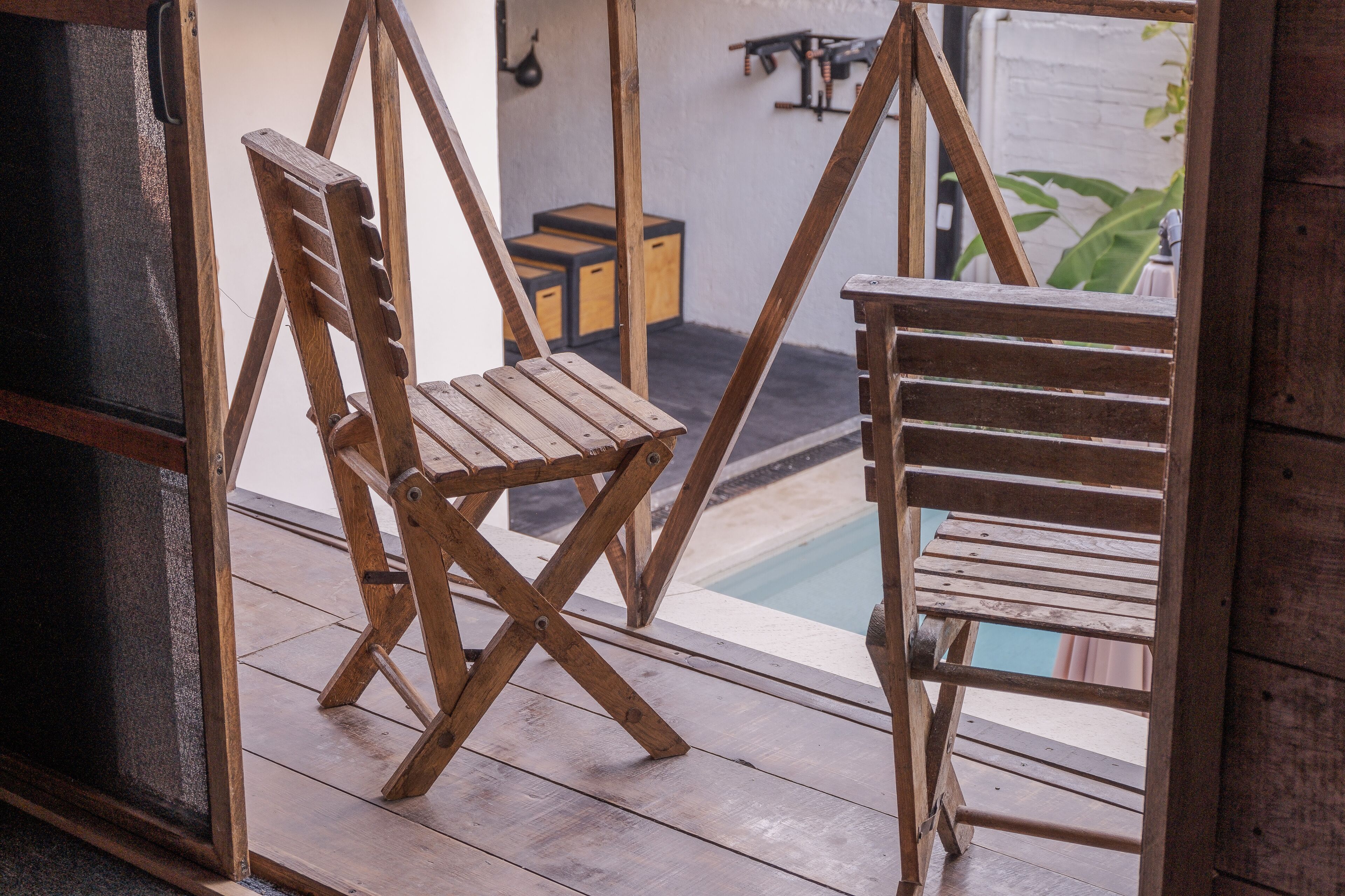 A wooden deck with two wooden chairs and a small table.