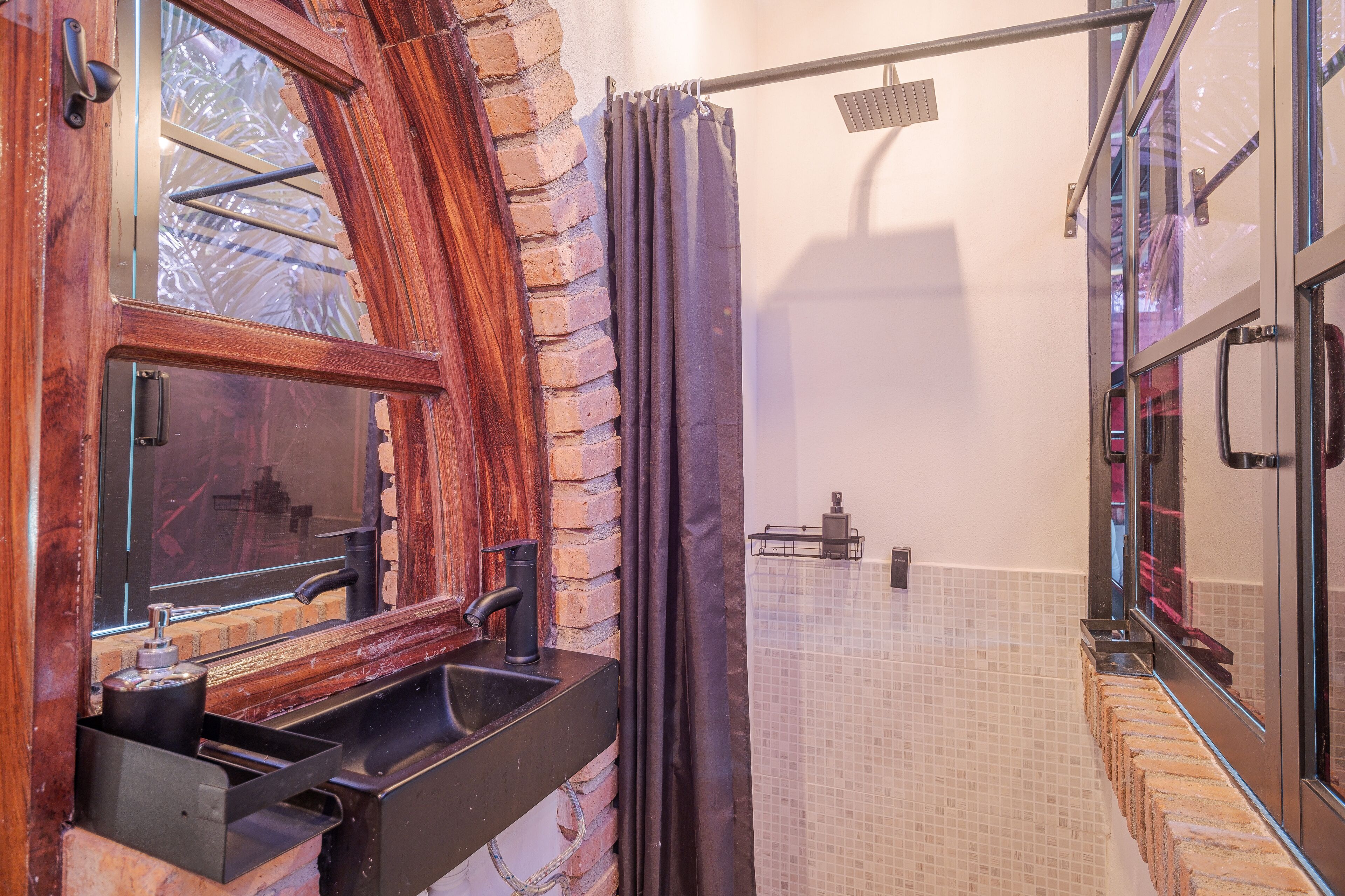 A bathroom with a wooden vanity, a shower area with a glass door, and a tiled floor.