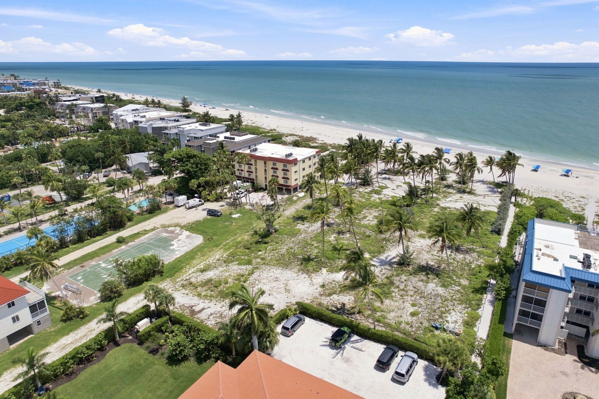A coastal hotel with a beach view, multiple buildings, and a parking area.