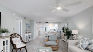 A spacious living area with a ceiling fan, wicker furniture, a white sofa, and a dining area in the background. - Breakers West C2 | Stunning Top Floor Beach Residence | Steps to the Sand (Sanibel)