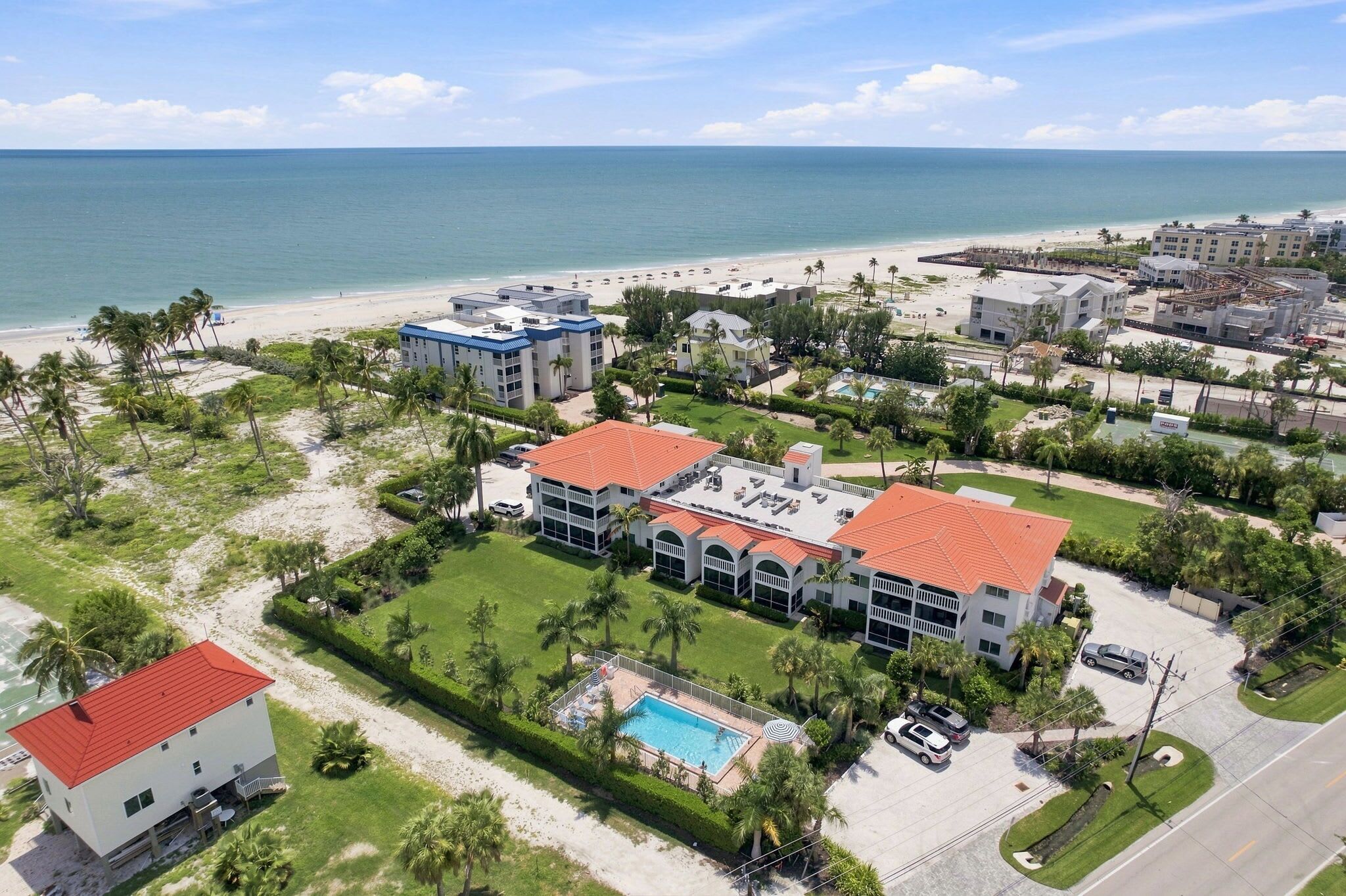 Ein Küstenhotel mit mehreren Gebäuden, einem Pool und Blick auf den Strand.