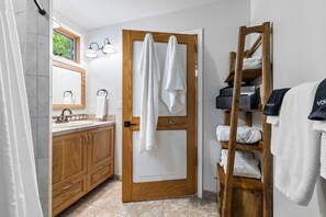 Un baño con puerta de madera, un lavabo con espejo y un perchero para toallas.