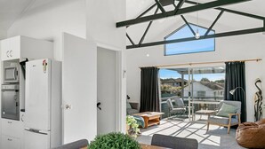 Eine moderne Küche mit Einbaugeräten, ein Essbereich mit Tisch und Stühlen sowie ein Balkon mit Blick auf die Umgebung.