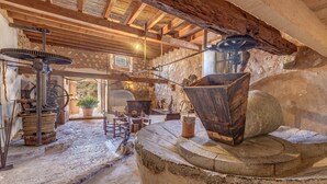 Ein rustikales Interieur mit Steinwänden, Holzbalken und einem großen Holzradmechanismus.
