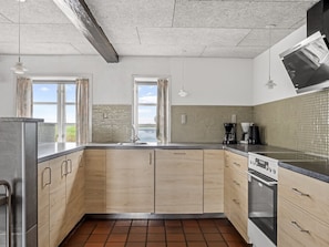 A modern kitchen with wooden cabinets, a stainless steel refrigerator, a built-in oven, and a tiled backsplash. - "Haralde" by Interhome (Bredebro)