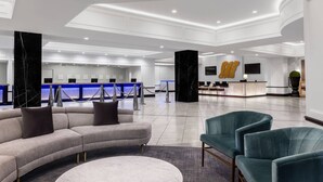 A spacious lobby with a reception desk, seating area, and a large marble column.