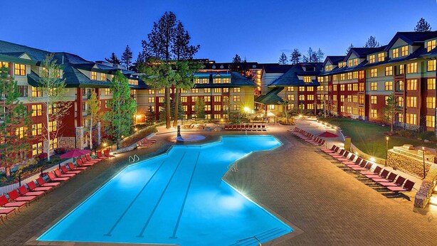 A large swimming pool surrounded by red chairs and lounge areas, with multiple hotel buildings in the background. - Marriott's Timber Lodge - Ski-In & Ski-Out - Sleeps 8! (South Lake Tahoe)