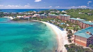 Um resort à beira-mar com villas privativas na praia, piscina e vista para o oceano.