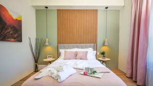 A neatly made bed with white and pink linens, a bedside table with a plant, and a wall-mounted artwork. - Your luxury vacation begins here! (Drumheller)