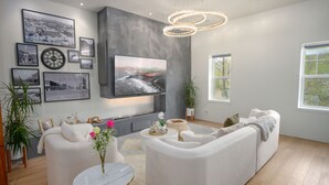 A modern living room with a large flat-screen TV, a fireplace, and a comfortable seating area. - Your luxury vacation begins here! (Drumheller)