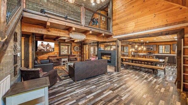 A spacious log cabin interior with a living area, dining space, and a fireplace.