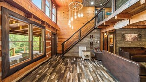 A wooden interior with a staircase, large windows, and a cozy seating area.