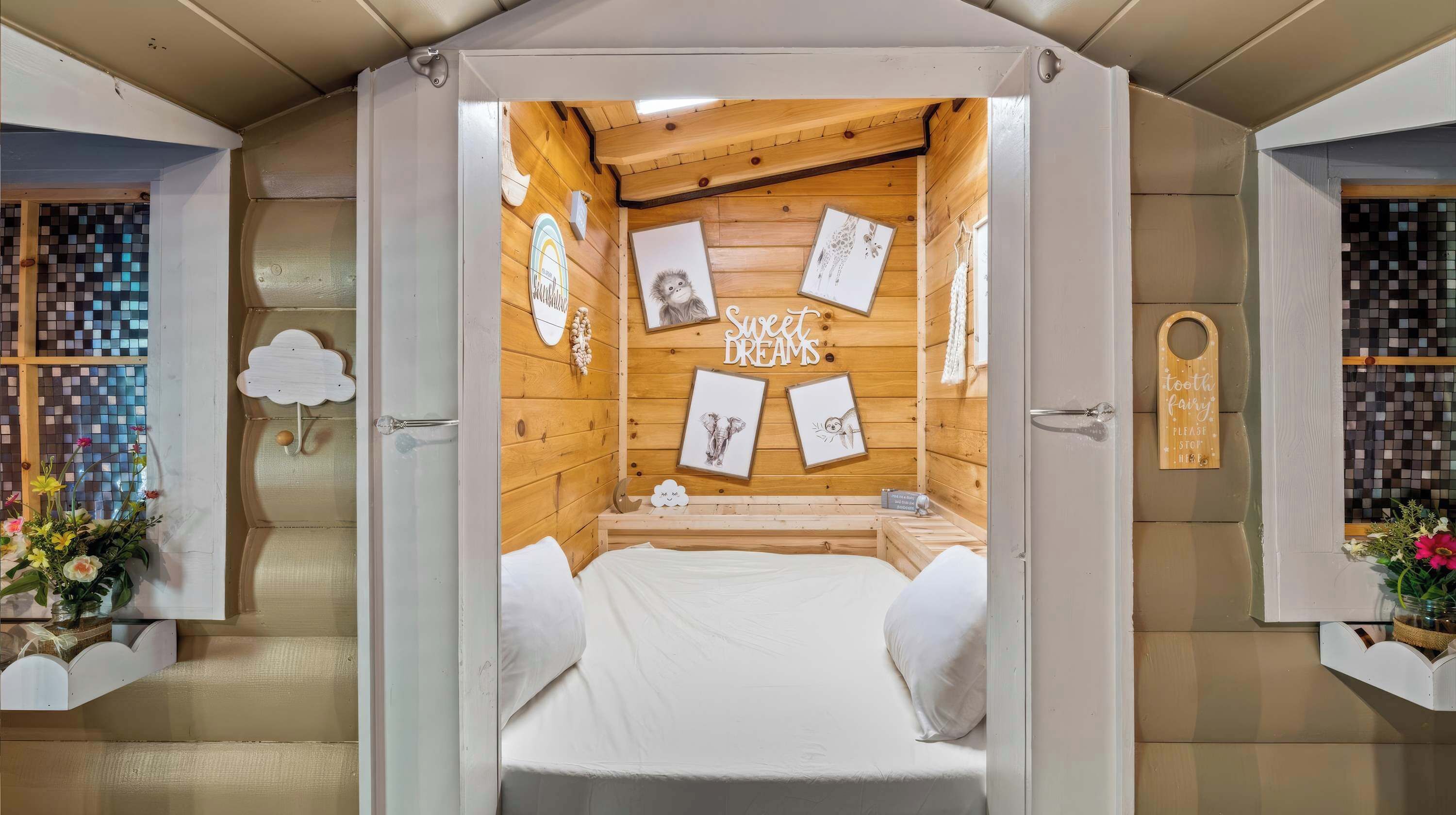A cozy room with a bed, framed pictures on the wall, and a wooden ceiling.