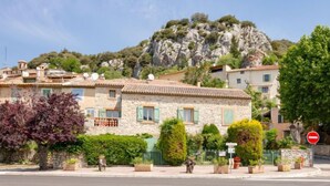 Un bâtiment en pierre avec un toit en tuiles, un balcon et une vue sur une colline rocheuse.