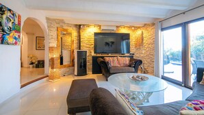 Un salon moderne avec un mur d’accent en pierre, un téléviseur à écran plat, une table basse en verre et un canapé confortable.