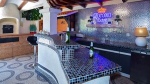 Un espace bar agrémenté d’une enseigne Corona Extra, d’un comptoir et d’un coin salon avec des chaises.
