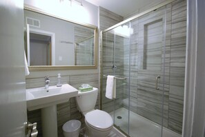 Ein modernes Badezimmer mit Duschkabine aus Glas, einem weißen Waschbecken und einer Toilette.