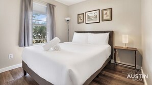 A neatly made bed with white linens, a bedside table with a lamp, and two framed pictures on the wall. - 5412 Pine xxxxxxxxxx (Austin)