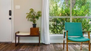 A room with a wooden bench, a potted plant, and a teal chair by a window with a view of trees. - 5412 Pine xxxxxxxxxx (Austin)