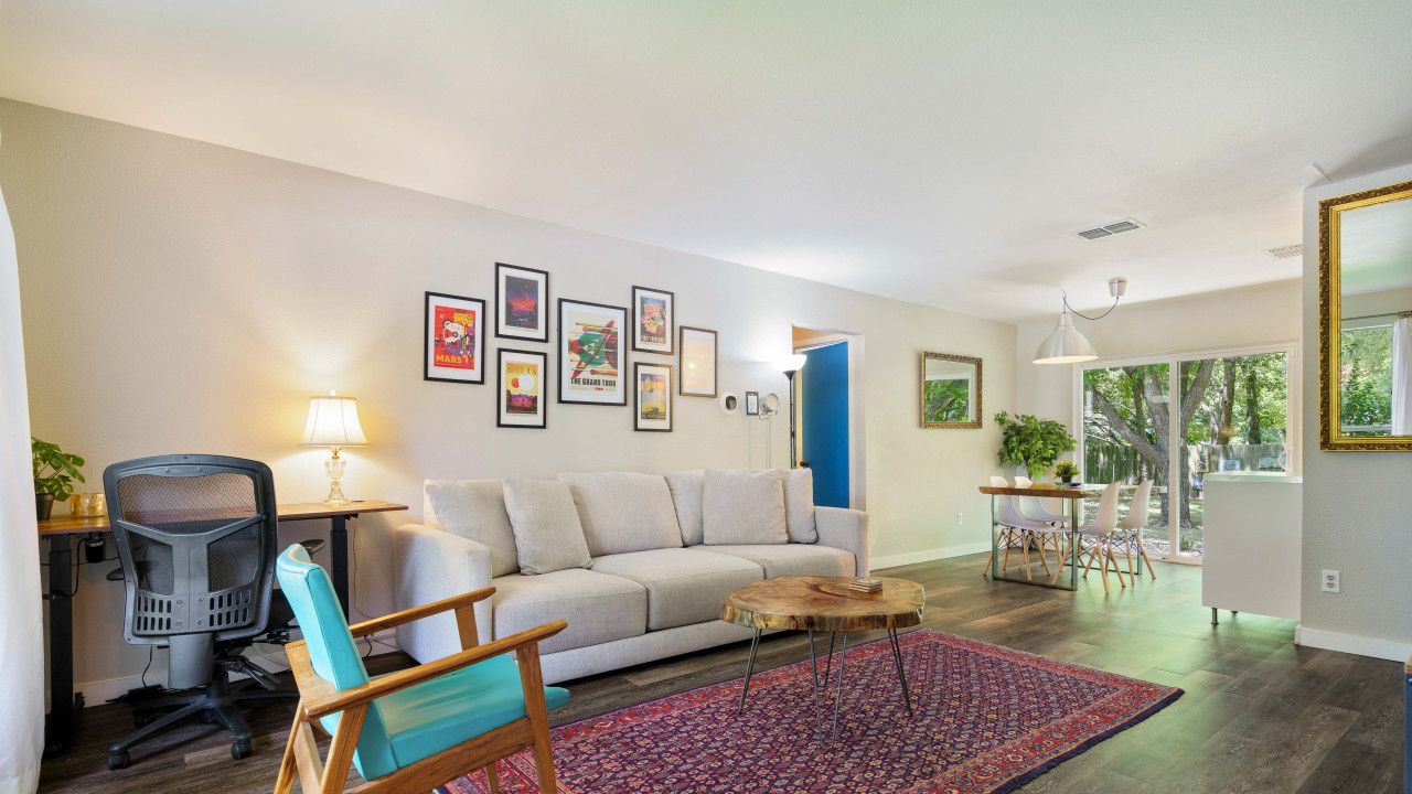 A modern living room with a sofa, a coffee table, a patterned rug, and a desk with a chair.