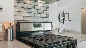 Een moderne keuken met een roestvrijstalen fornuis, een tegelwand van baksteen en een wit aanrecht.