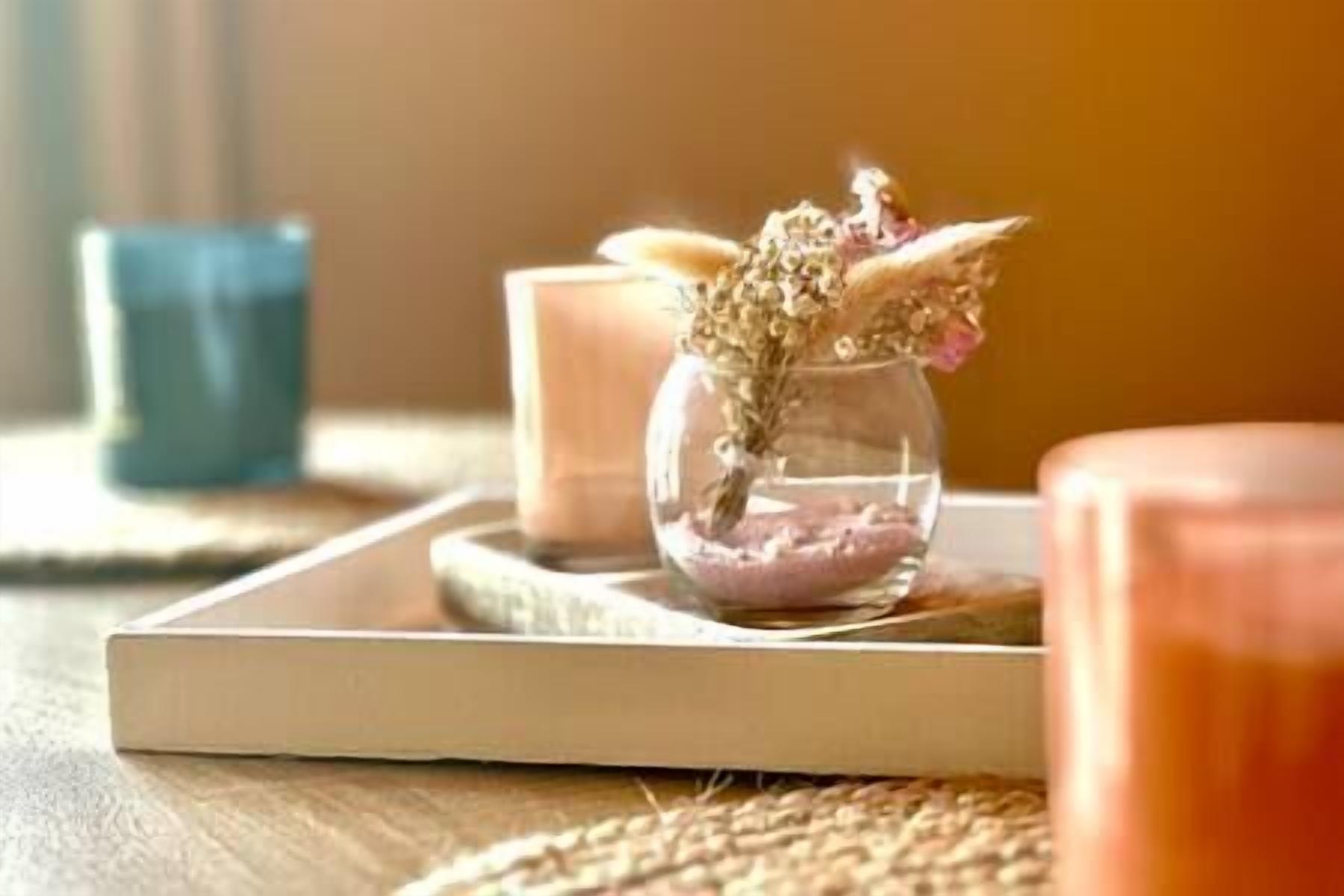 A candle holder with dried flowers on a tray.