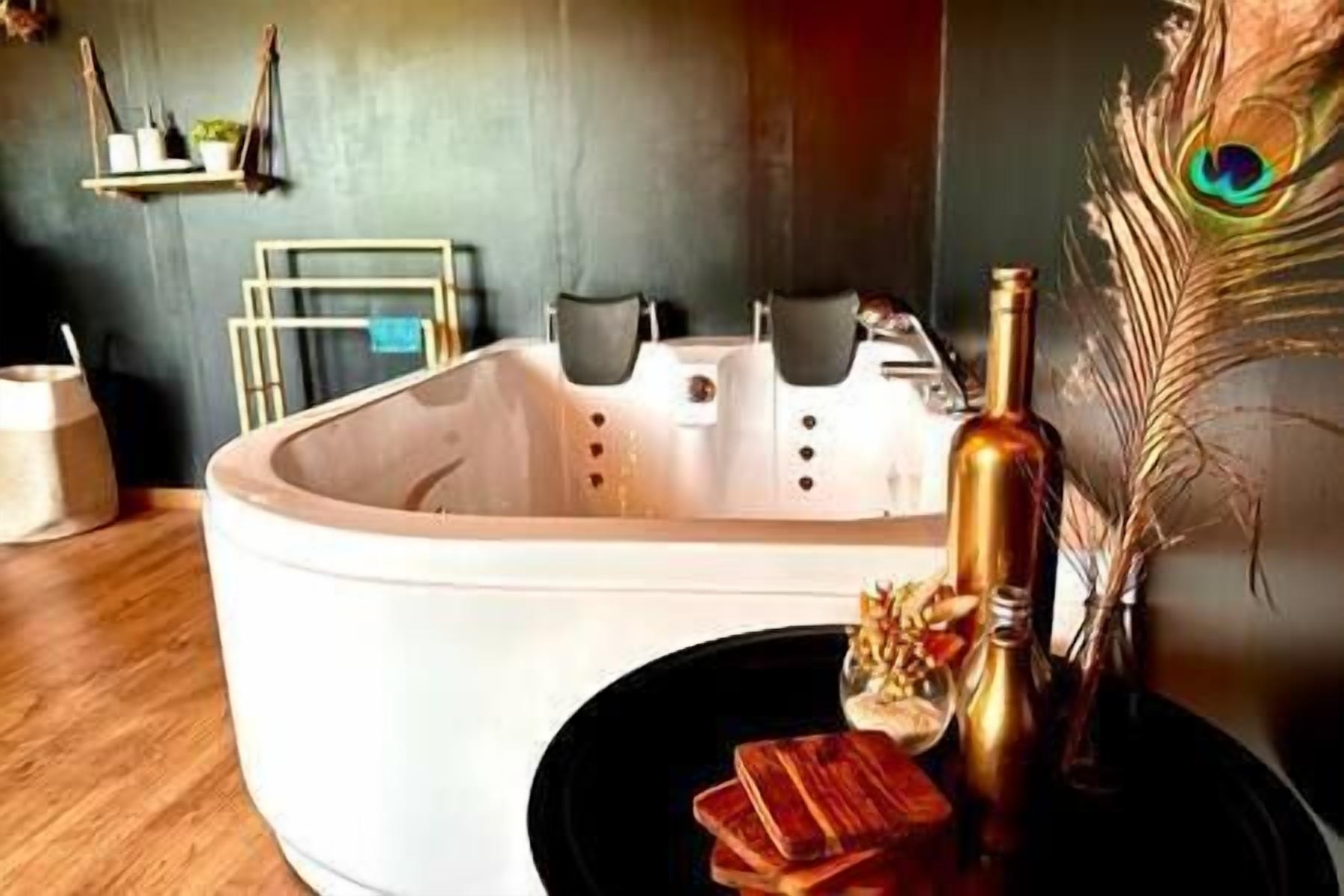 Une salle de bain moderne avec une baignoire sur pieds, un vase décoratif et un plateau en bois.