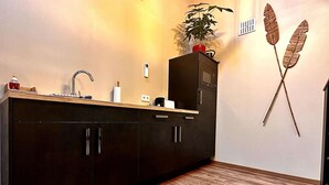 A modern kitchen with dark cabinets, a wooden countertop, a sink, and a plant on the counter. - Hour House 2 - Honeymoon (Houyet)