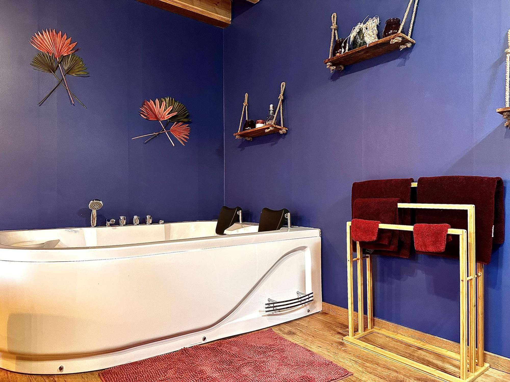 A modern bathroom with a freestanding bathtub, wooden shelves with towels, and decorative wall art.