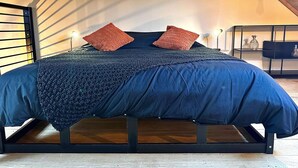 A bedroom with a bed, two wall-mounted lights, and a wooden ceiling. - Hour House 2 - Honeymoon (Houyet)