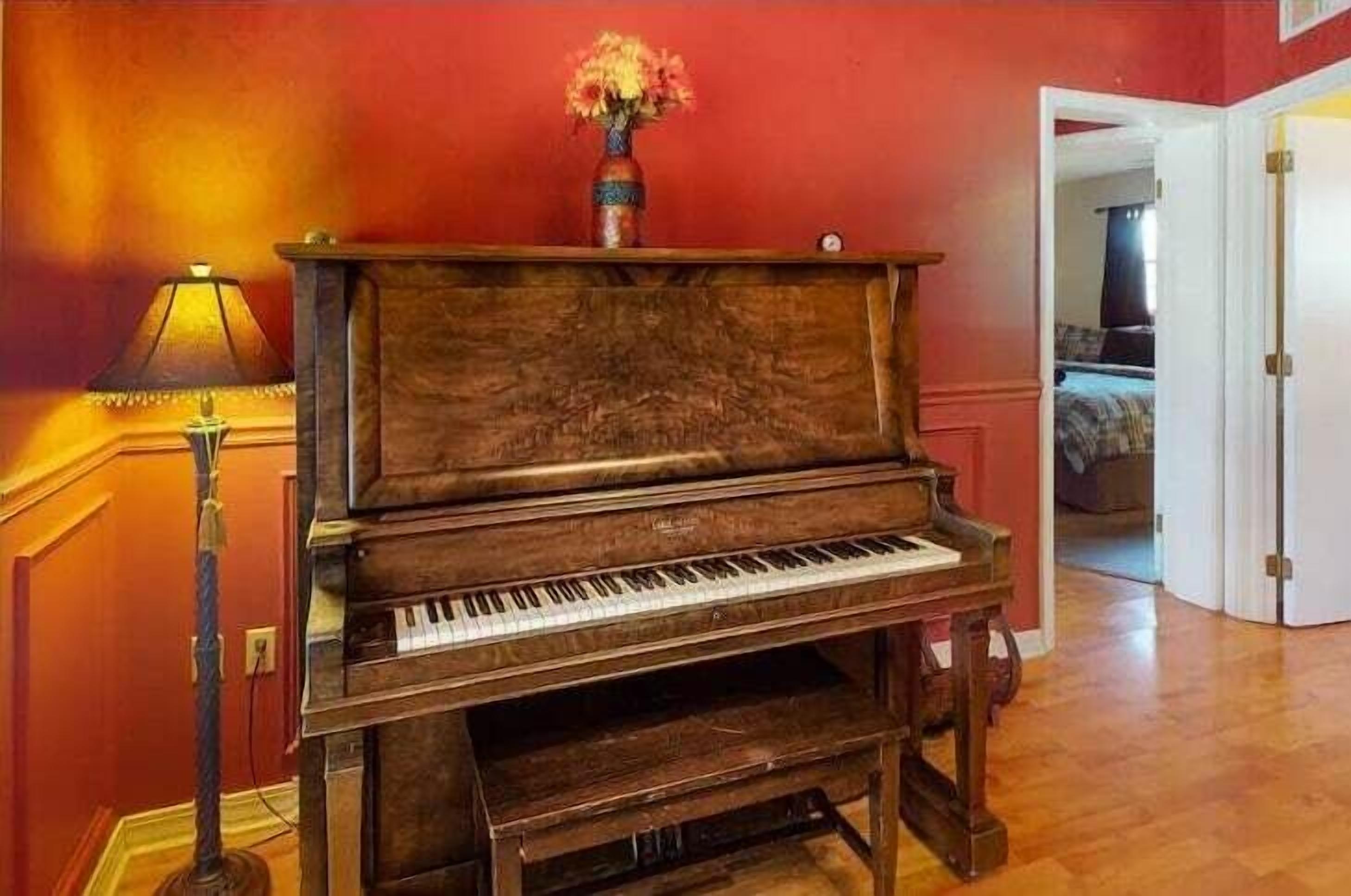 Un piano à queue dans une pièce aux murs rouges et au plancher en bois.