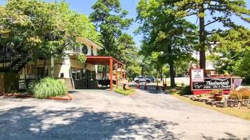 A building with a covered entrance, a sign for 'Trader Windy', and a parking area with trees and a clear sky.