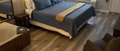 Un dormitorio con cama, lámparas de noche, una silla, una mesita y una ventana.