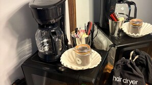 Een keuken met een koffiezetapparaat, magnetron en een föhnzak op het aanrecht.