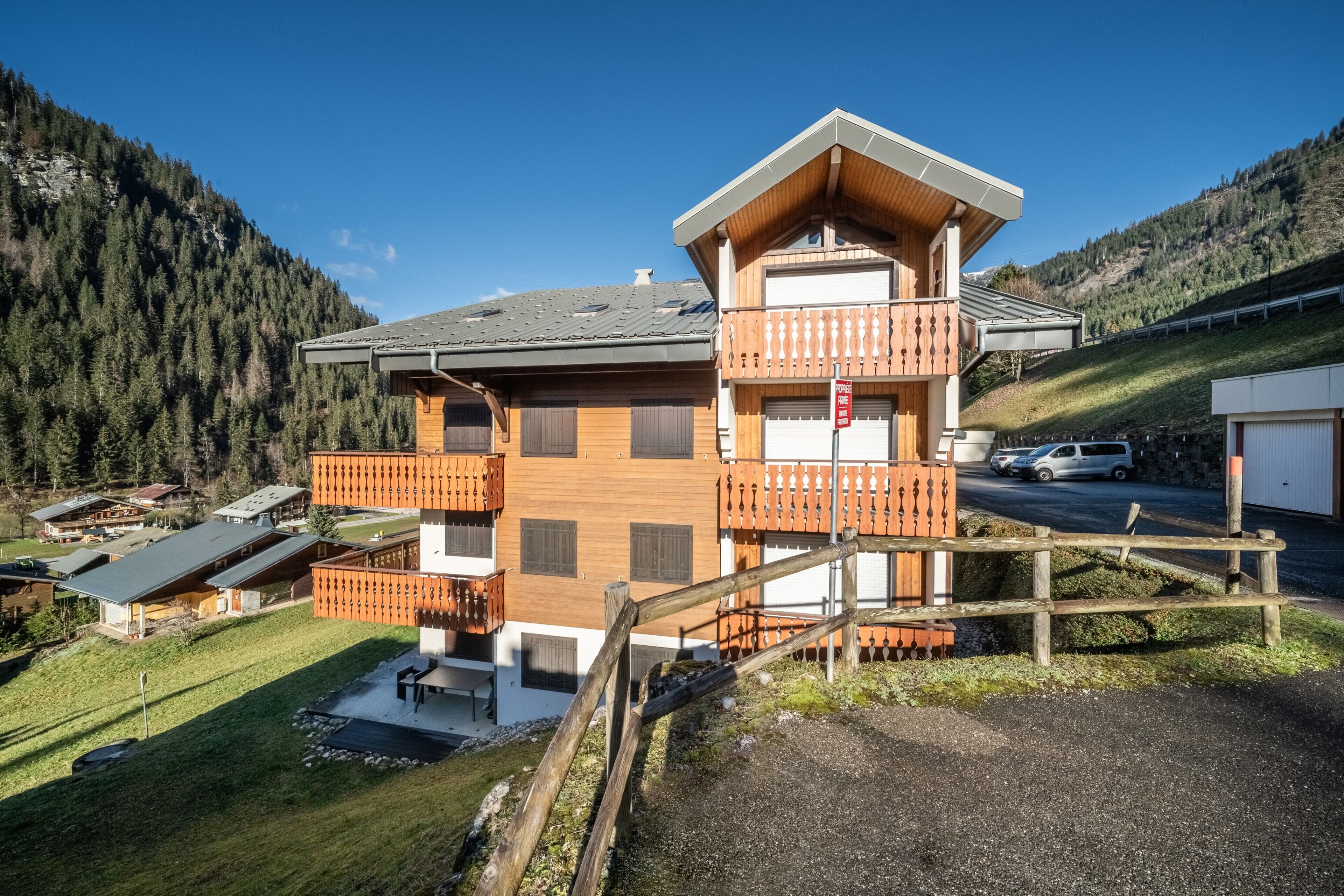 A two-story wooden house with a balcony, a garage, and a driveway.