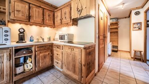 A kitchen with wooden cabinets, a microwave, a kettle, and a toaster. - T3 Chatel Apartment with Mountain View, Private Terrace and Balcony (chatel)