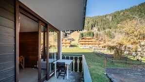 A balcony with a table and chairs, a view of a mountain, and a building with multiple windows. - Studio 'Ch âtel - At the Foot of Linga' with Mountain View and Balcony (Châtel)