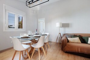 Un coin repas avec une table en verre, des chaises blanches et un canapé marron.