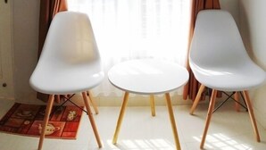 A room with two white chairs, a small table, and a window with brown curtains. - Omah Bondi Family Homestay by FH Stay (Yogyakarta)
