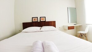 A hotel room with a large bed, a wooden headboard, two framed pictures, a small desk with a chair, and a mirror. - Omah Bondi Family Homestay by FH Stay (Yogyakarta)