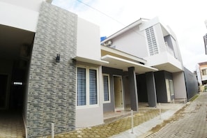 Une maison moderne à deux étages, dotée d’un toit plat, de grandes fenêtres et d’une façade en pierre.