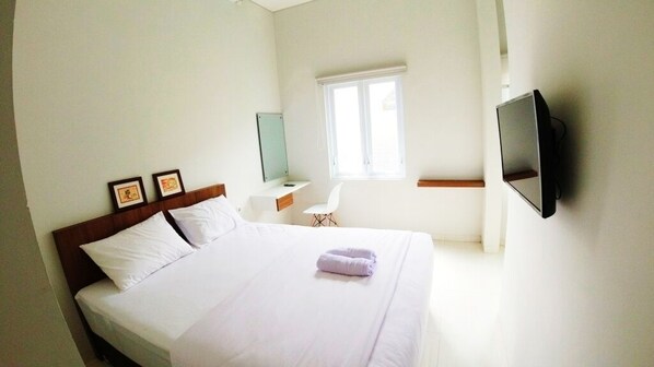 Une chambre d’hôtel avec un lit, un bureau, une chaise, une télévision et une fenêtre.