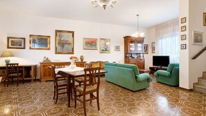 Een woonkamer met een eethoek, een televisie en een trap.