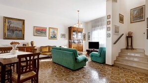Een woonkamer met een bank, televisie en een trap.