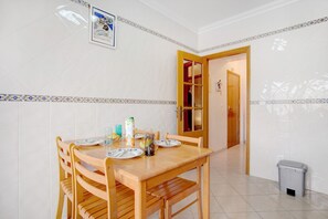 A dining area with a wooden table, chairs, and a tiled wall with a decorative border.