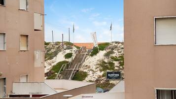 Ein Gebäude mit einem Schild für eine Surfschule, einer Treppe zu einem Sandbereich und einem klaren Himmel.