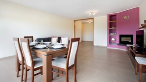 Een eetruimte met een houten tafel en stoelen, een televisie en een open haard.
