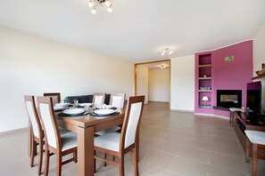 A dining area with a wooden table and chairs, a TV, and a fireplace.